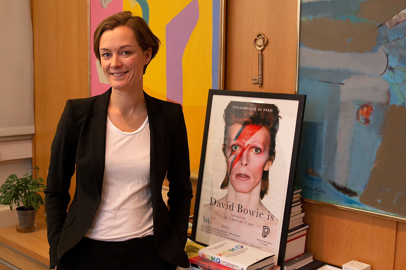 Anette Trettebergstuen på kontoret foran en plakat av David Bowie