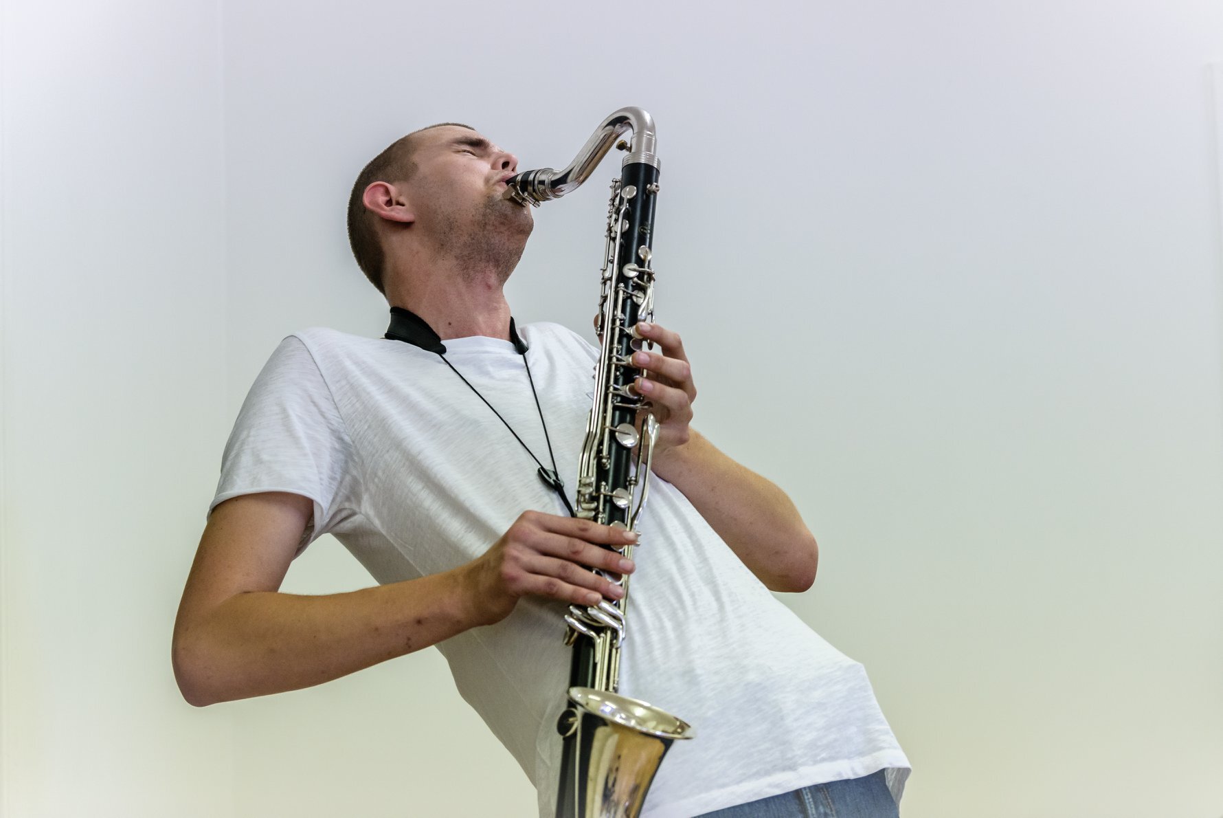 Mann i hvit skjorte lener seg bakover mens han spiller klarinett