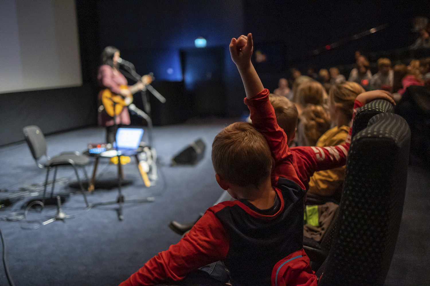 Barn i kultursal med opprakt hånd