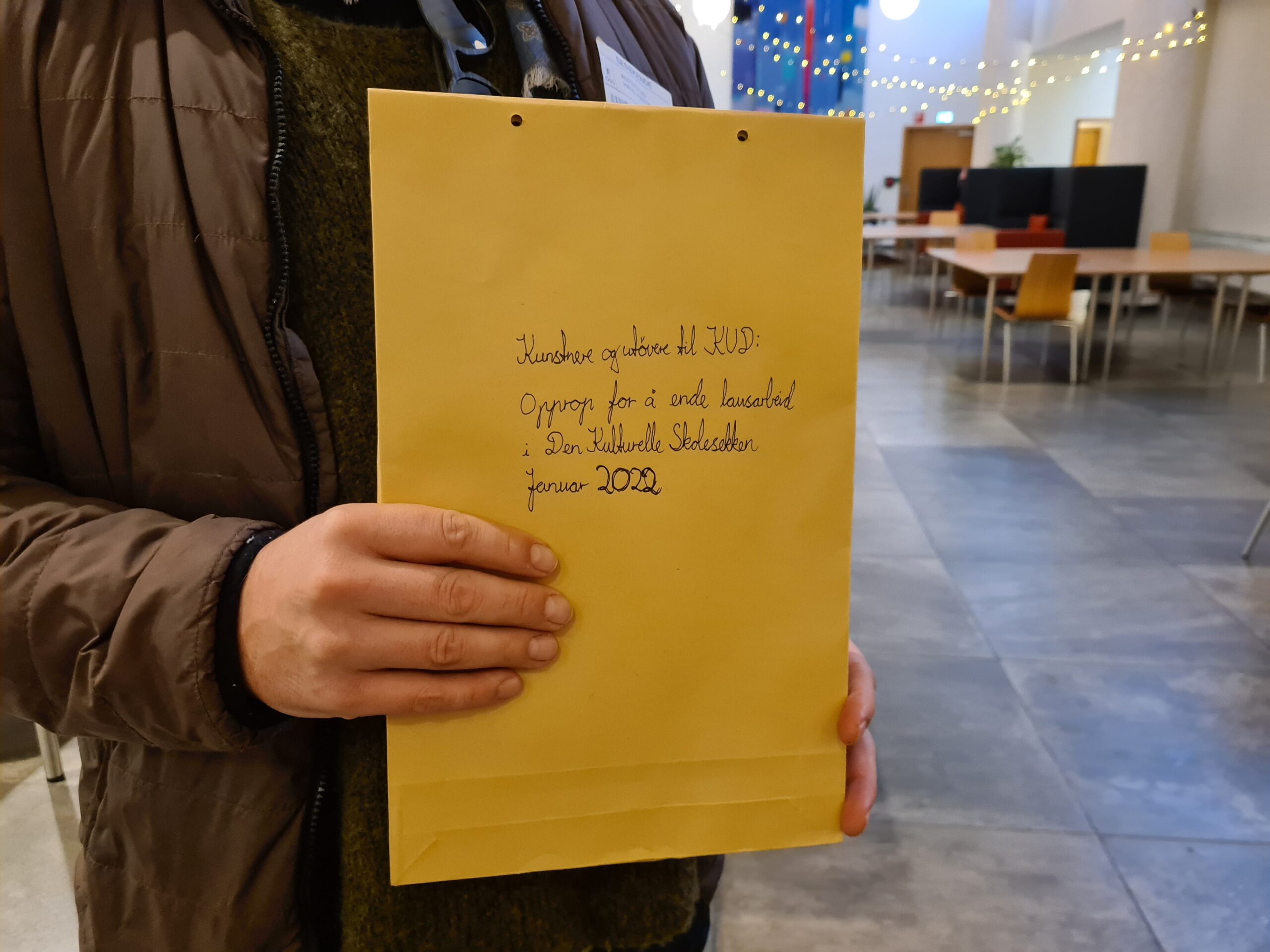 Brun konvolutt med pen håndskrift holdt av en hånd