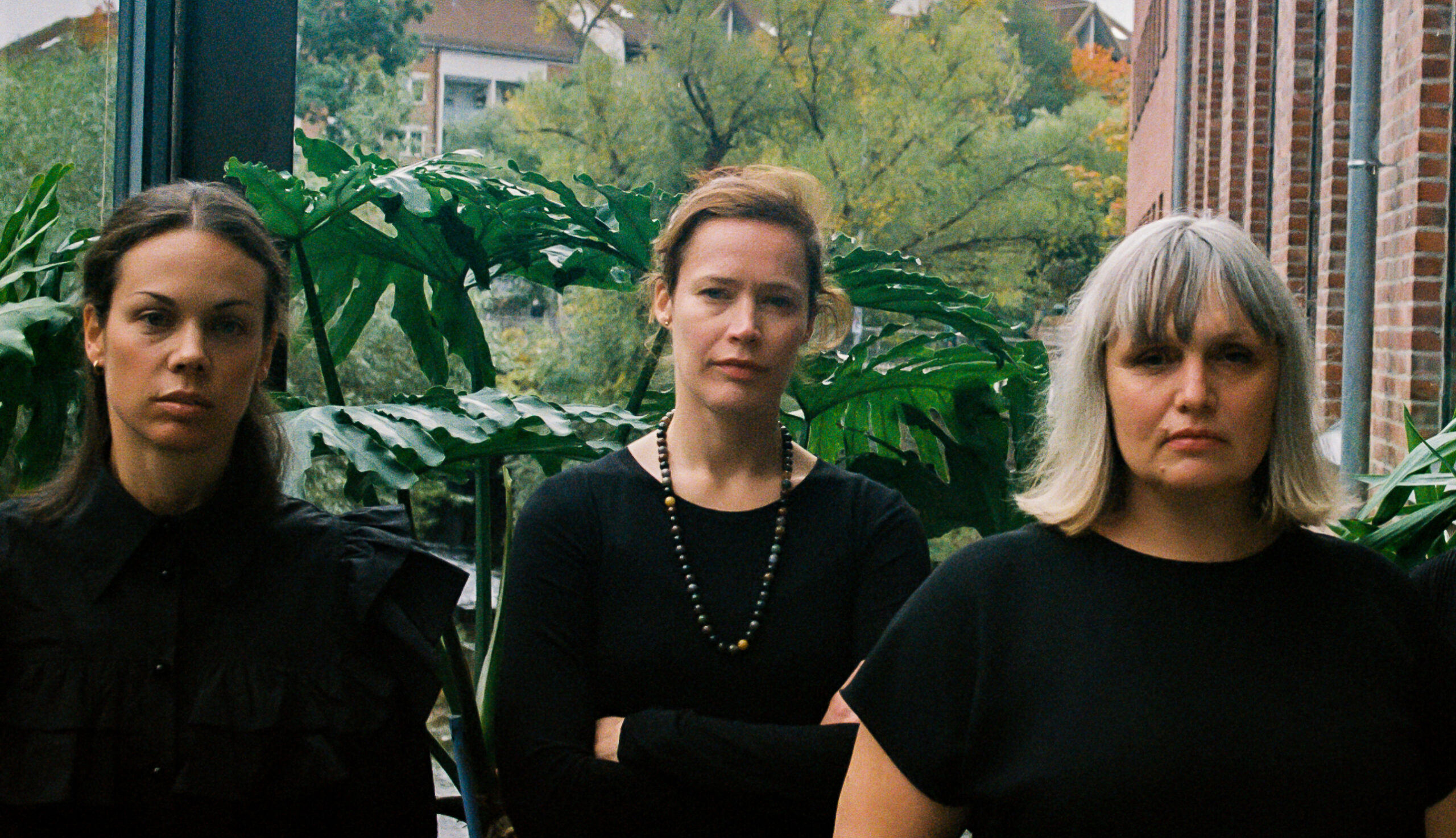 Tre myndige kvinner kledd i sort på balkong