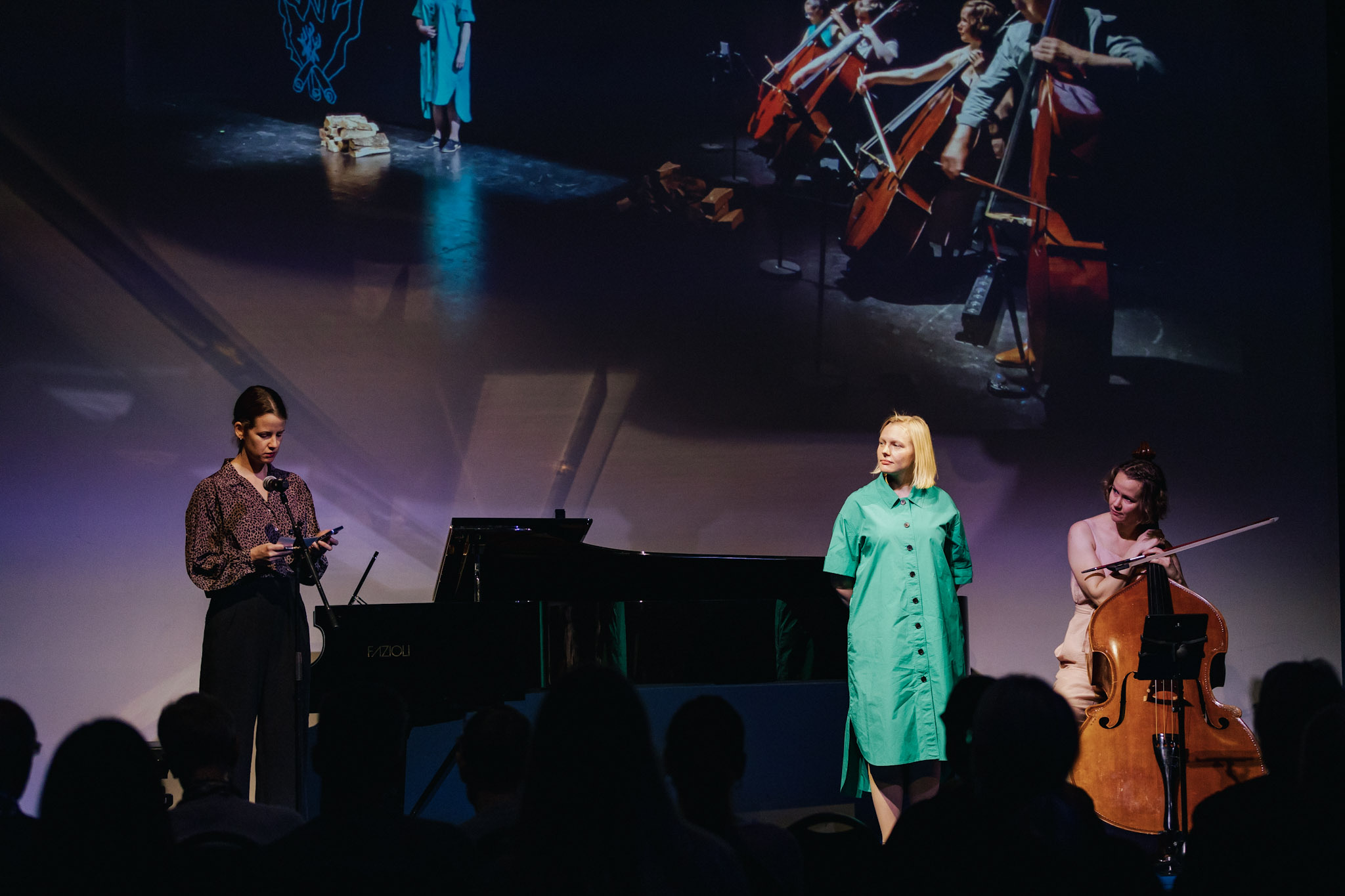 Tre kvinnelige musikere på scene, til høyre kontrabass, i midten sanger og til venstre konferansier