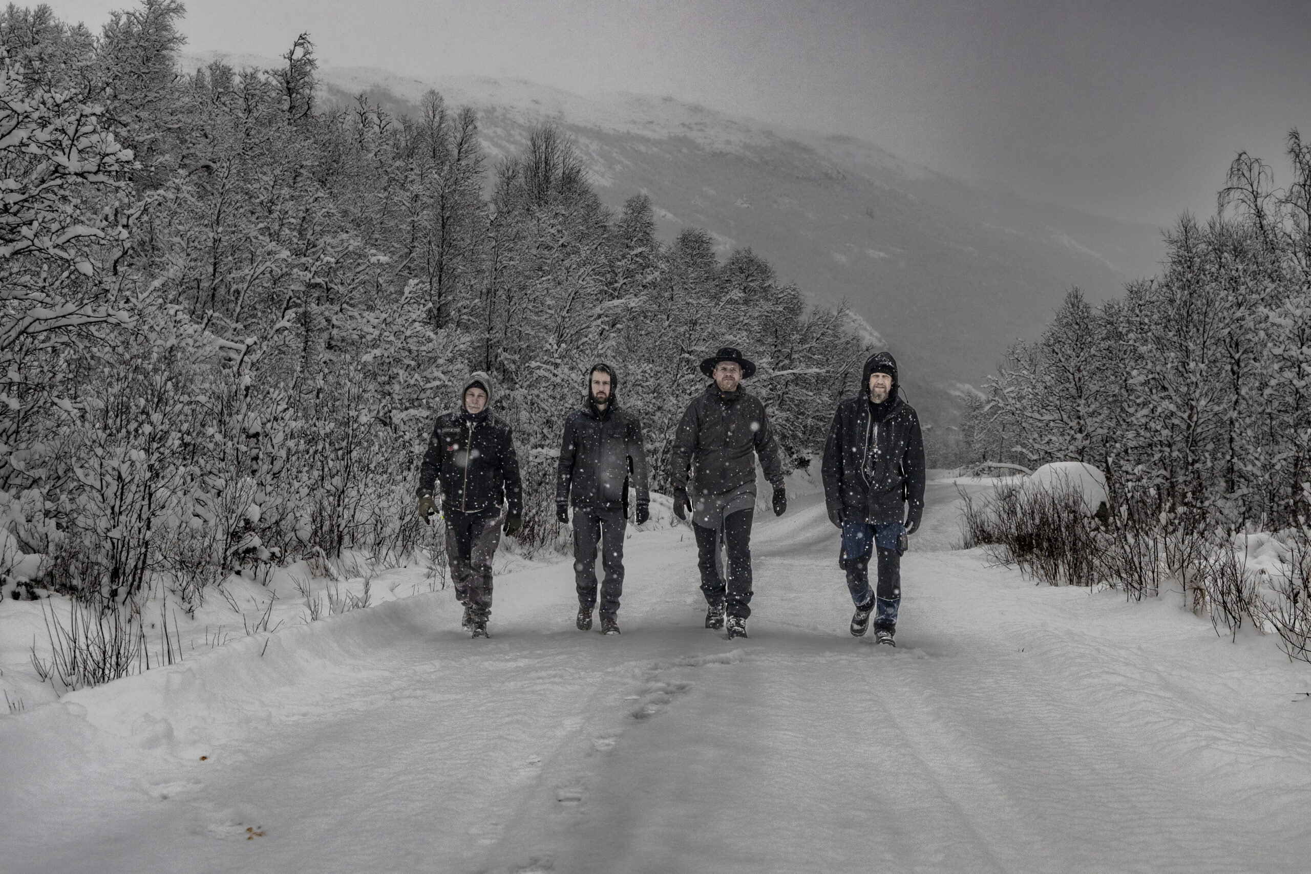 Fire menn i svart på snødekket vintervei