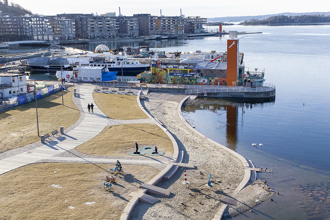 Strandpromenade og kulturbåde i forgrunnen for blokkbebyggelsen Sørenga