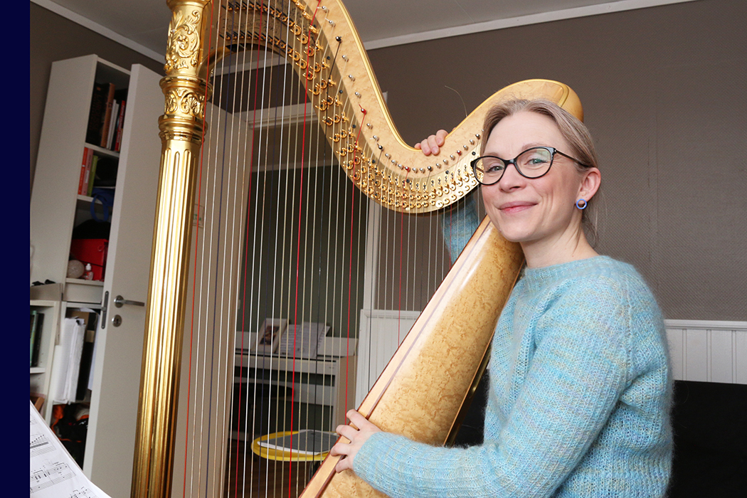Kvinne med stor gammeldags pen harpe i et ganske vanlig rom